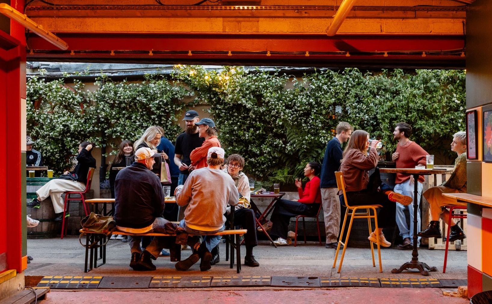 People enjoying beers and cocktails in the brewery with the doors open and sun shining in